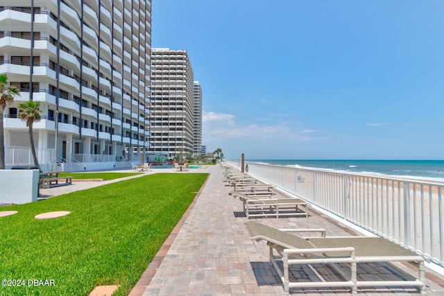 view of home's community featuring a lawn, a water view, and a beach view