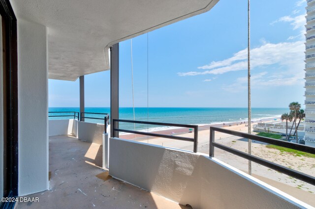 balcony with a water view and a view of the beach