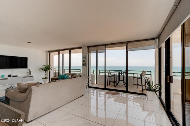 living room with plenty of natural light, a water view, and a wall of windows