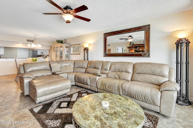 living room with ceiling fan with notable chandelier and a textured ceiling