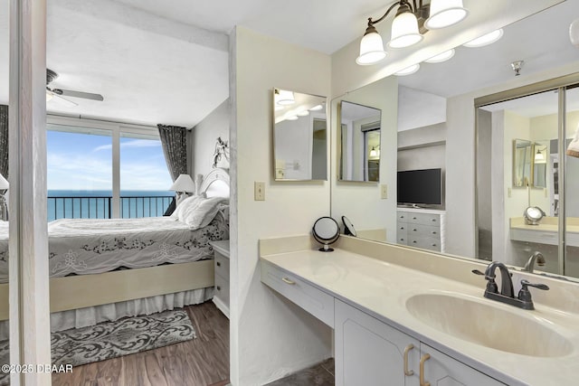 bathroom featuring vanity, hardwood / wood-style floors, a water view, and ceiling fan