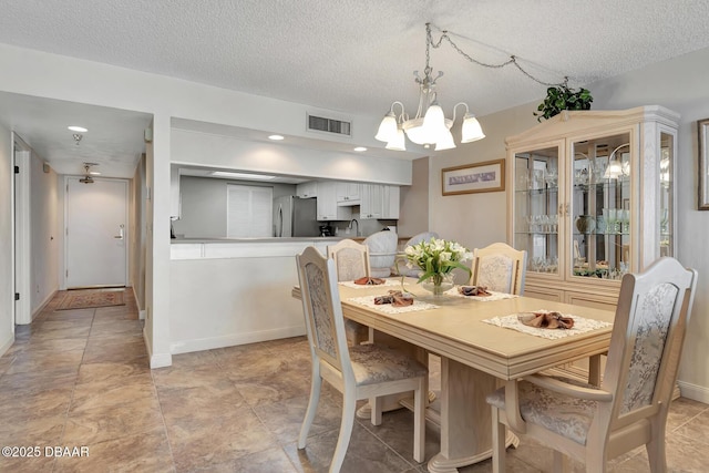 dining space featuring a textured ceiling, sink, and a notable chandelier