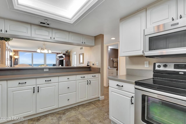 kitchen featuring appliances with stainless steel finishes, white cabinetry, and a notable chandelier