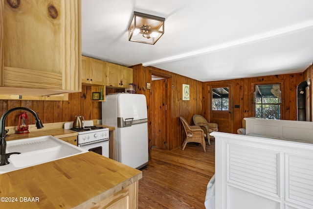 kitchen featuring light brown cabinets, white appliances, sink, wooden walls, and dark hardwood / wood-style flooring