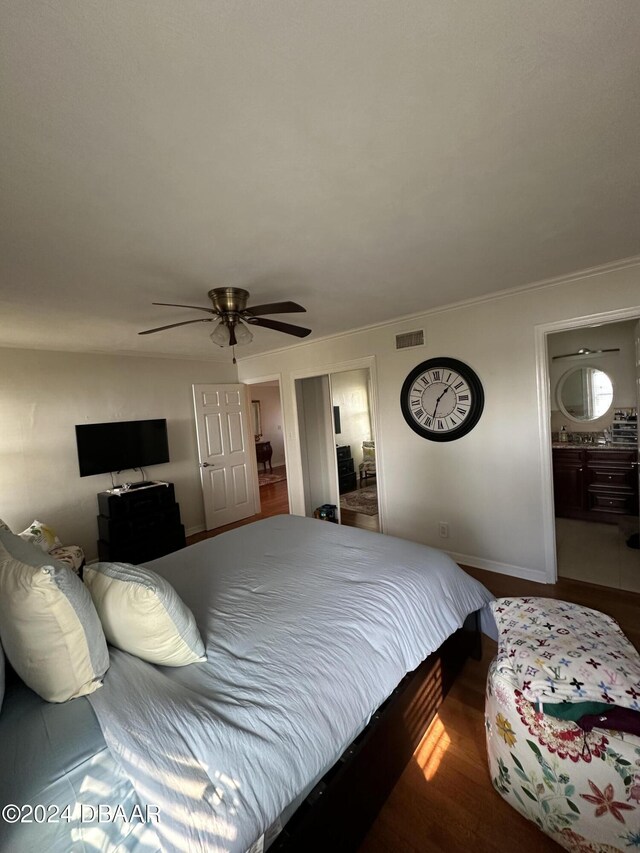 bedroom with hardwood / wood-style floors, ceiling fan, crown molding, and ensuite bath