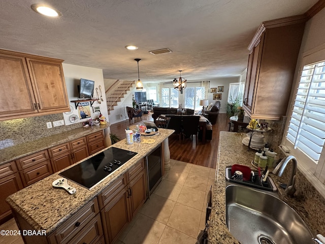 kitchen with black electric stovetop, sink, decorative light fixtures, an inviting chandelier, and light tile patterned flooring