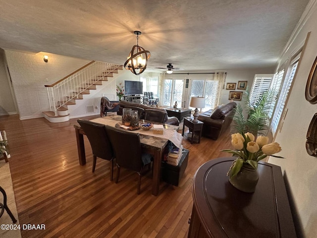 dining room with a textured ceiling, ceiling fan with notable chandelier, hardwood / wood-style flooring, and crown molding