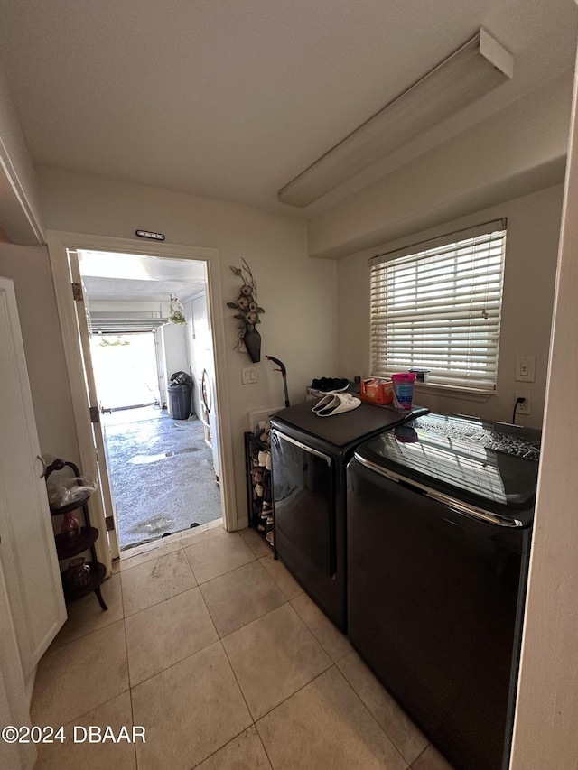 clothes washing area with light tile patterned floors and washer and dryer