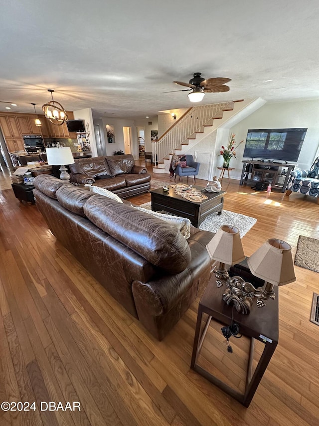 living room with hardwood / wood-style flooring and ceiling fan with notable chandelier