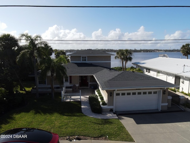 view of front facade with a garage, a water view, and a front lawn