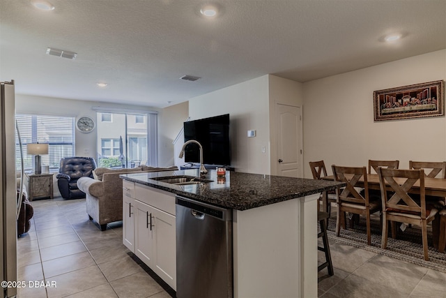 kitchen featuring sink, appliances with stainless steel finishes, white cabinetry, an island with sink, and a kitchen bar