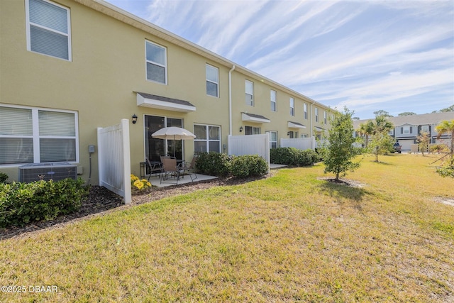 rear view of house featuring cooling unit, a patio, and a lawn