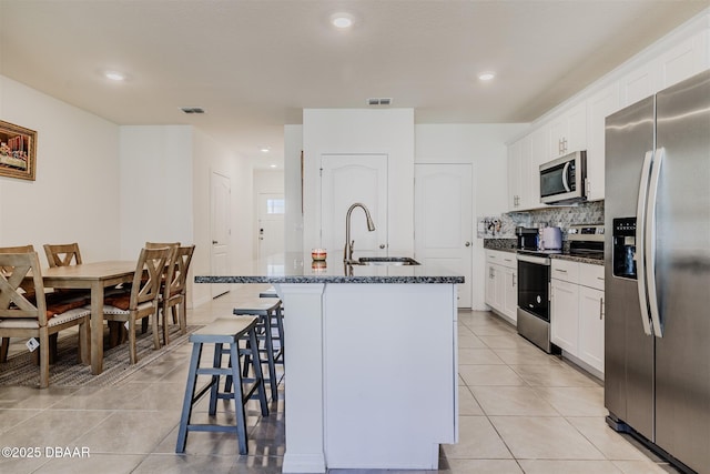 kitchen with stainless steel appliances, sink, an island with sink, and white cabinets