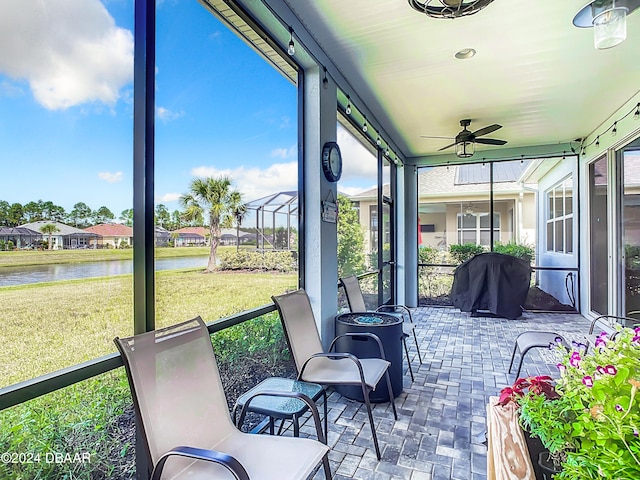 sunroom / solarium with a water view and ceiling fan