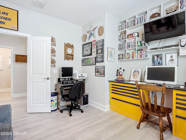 home office featuring light hardwood / wood-style flooring and a textured ceiling