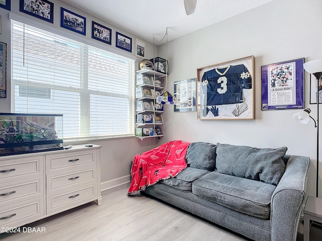 living room with a textured ceiling, light wood-type flooring, a healthy amount of sunlight, and ceiling fan