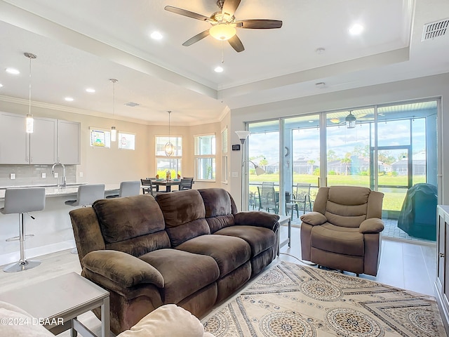 living room with a wealth of natural light, ceiling fan, and crown molding