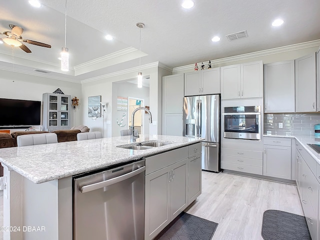 kitchen with sink, ornamental molding, a kitchen island with sink, pendant lighting, and appliances with stainless steel finishes