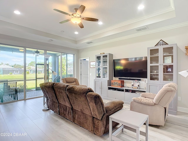 living room with ceiling fan, a raised ceiling, light hardwood / wood-style flooring, and ornamental molding