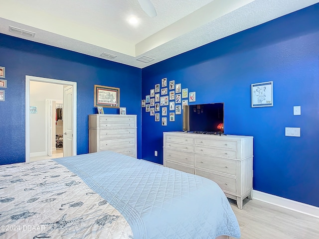 bedroom with light hardwood / wood-style floors, a textured ceiling, and ceiling fan