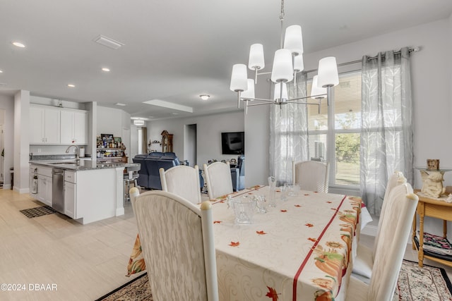 dining space with sink, a chandelier, and light wood-type flooring