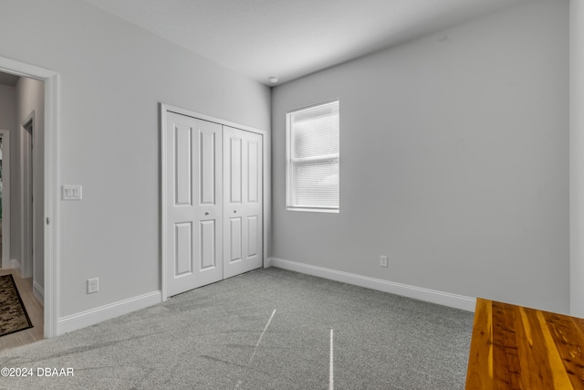 unfurnished bedroom featuring carpet, baseboards, and a closet