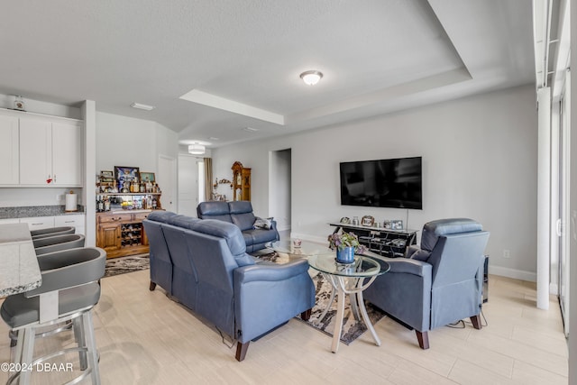 living area with baseboards and a tray ceiling