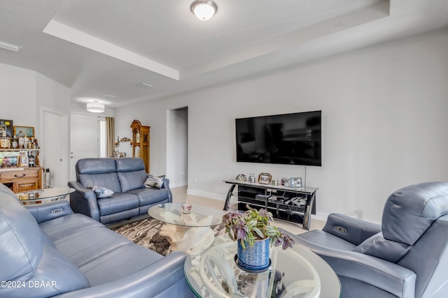 living room featuring a tray ceiling, a textured ceiling, and baseboards