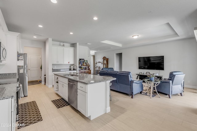 kitchen with sink, white cabinets, stainless steel appliances, and a center island with sink