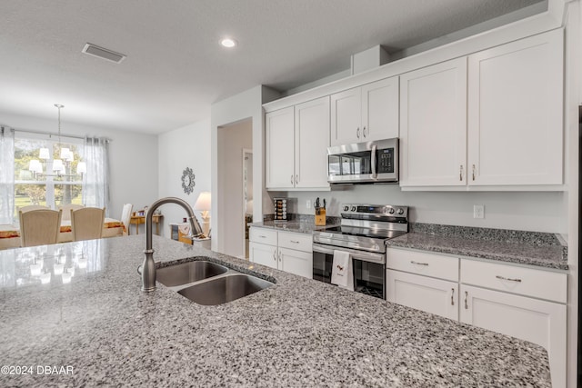 kitchen with a sink, visible vents, white cabinetry, appliances with stainless steel finishes, and an inviting chandelier