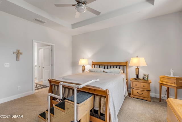 bedroom featuring light colored carpet, ceiling fan, and a tray ceiling