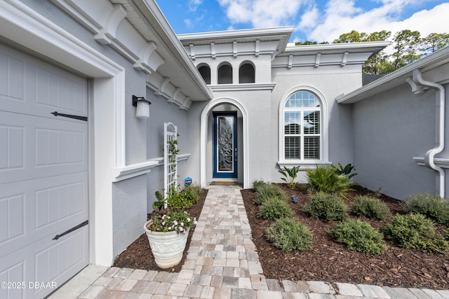 doorway to property featuring an attached garage and stucco siding