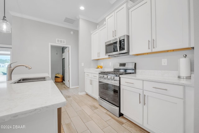 kitchen with decorative light fixtures, appliances with stainless steel finishes, sink, and white cabinets