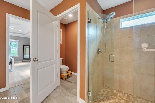 bathroom featuring wood-type flooring, a shower with door, and toilet