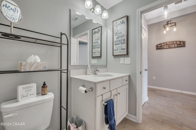 bathroom featuring wood-type flooring, toilet, and vanity