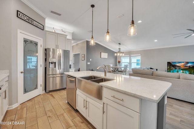 kitchen featuring crown molding, appliances with stainless steel finishes, decorative light fixtures, sink, and an island with sink