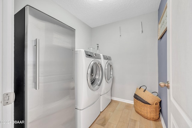 laundry area with light hardwood / wood-style floors, a textured ceiling, and separate washer and dryer