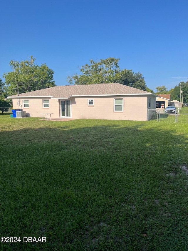 rear view of house with a yard and cooling unit