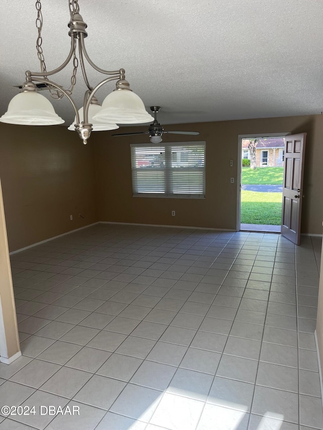 tiled spare room with ceiling fan with notable chandelier and a textured ceiling