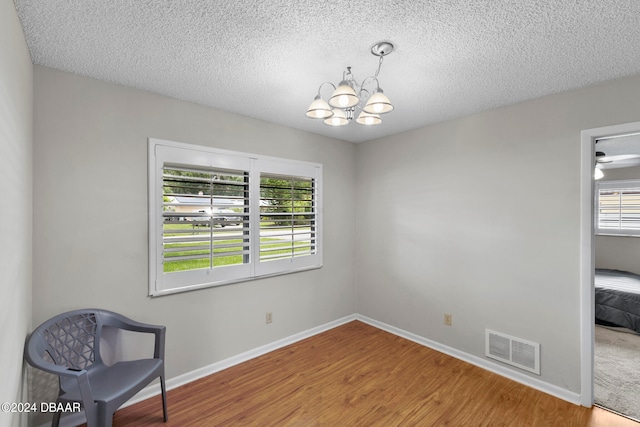 unfurnished room with wood-type flooring, a healthy amount of sunlight, and a textured ceiling