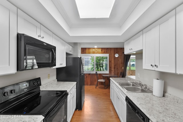 kitchen with white cabinets, light hardwood / wood-style flooring, black appliances, and sink