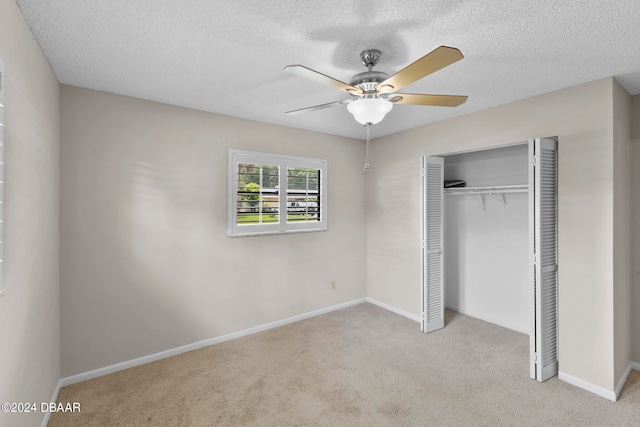 unfurnished bedroom with a closet, a textured ceiling, light carpet, and ceiling fan