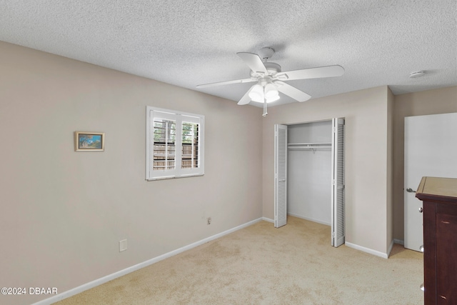 unfurnished bedroom featuring ceiling fan, light carpet, a closet, and a textured ceiling