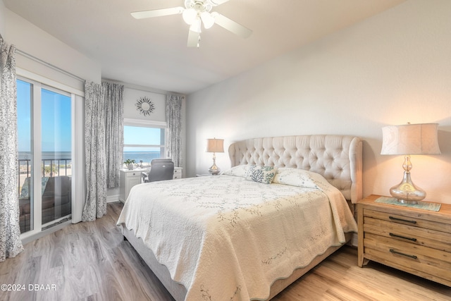 bedroom with hardwood / wood-style floors, a water view, and ceiling fan