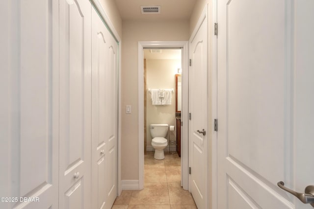 hall featuring light tile patterned floors, baseboards, and visible vents