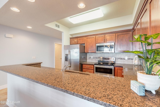 kitchen with tasteful backsplash, visible vents, light stone counters, stainless steel appliances, and a sink