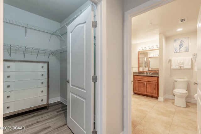 spacious closet with light tile patterned flooring, visible vents, and a sink