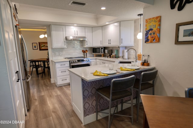 kitchen featuring sink, hanging light fixtures, kitchen peninsula, white cabinets, and appliances with stainless steel finishes