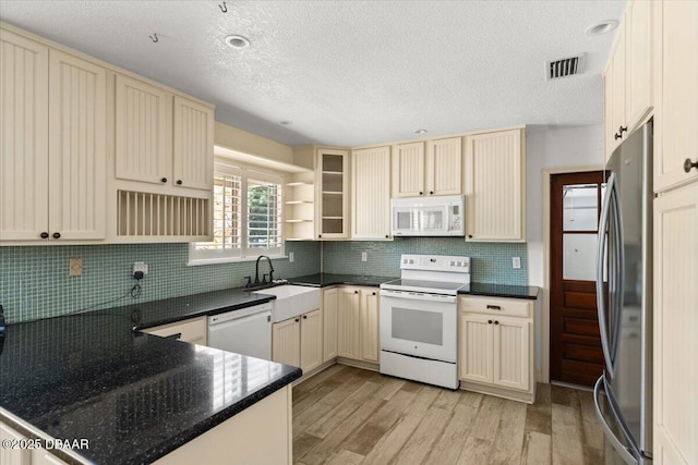 232 Chippewa Cir, Ormond Beach, FL 32174 - kitchen with white appliances, cream cabinets, open shelves, light wood-type flooring, and a peninsula