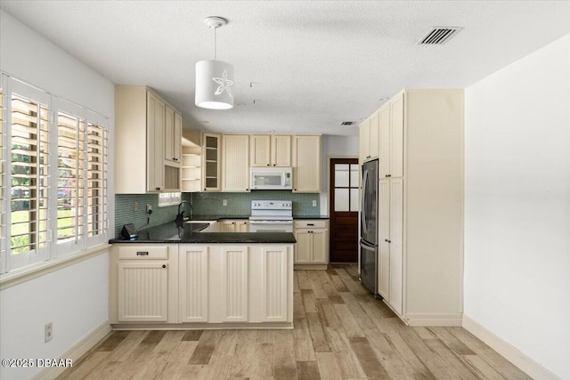 232 Chippewa Cir, Ormond Beach, FL 32174 - kitchen featuring white appliances, a peninsula, dark countertops, light wood-style floors, and tasteful backsplash
